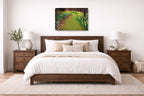 Canvas Print hanging in a Bedroom with wooden bed, white bedding, and a painting of a garden path on the wall.