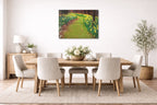 Dining room with wooden table and chairs, floral arrangement, and metal wall art of a garden path.