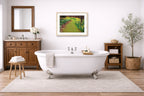 Oak-framed wall art hanging in a bathroom with a freestanding bathtub, wooden cabinet, and decorative elements.