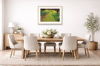 Oak framed wall art hanging in a dining room with wooden table and chairs, artwork, and plants.