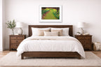 Bedroom with a wooden bed, white bedding, and white framed artwork on the wall.