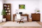 White framed photo on a home office wall with a wooden desk, chair, bookshelf, and decorative items.