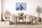 Pelican Posing against a blue sky printed on aluminum metal with wall anchors. Hung on a dining room wall.