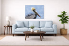 Pelican Posing against a blue sky printed on aluminum metal with wall anchors. Hung on a living room wall.