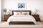 Pelican Posing against a blue sky printed on fine art paper, framed on a white frame and matted. Hung on a bedroom room wall