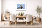 Pelican Posing against a blue sky printed on fine art paper, framed on a white frame and matted. Hung on a dining room wall.