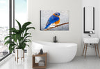 Painting of a bluebird on a branch by Carol Decker, printed on a canvas wrap hanging on a wall in the bathroom.