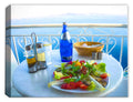 Still life photo of a food setting in Greece overlooking the blue water printed on a canvas wrap